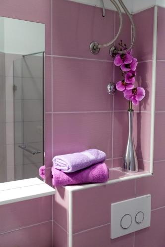 a pink bathroom with purple towels and a vase with flowers at Apartments Nenich Aves in Žman