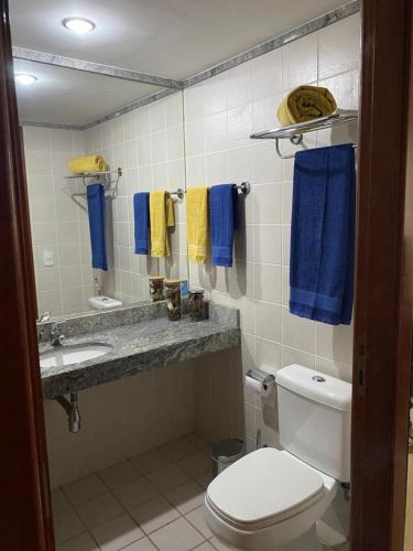 bagno con servizi igienici, lavandino e asciugamani blu di Flat encantador com piscina e área de lazer a Brasilia