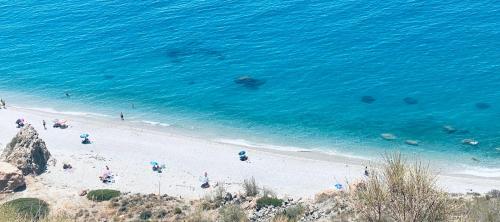 a beach with people and umbrellas and the ocean at Résidence Bario H in Al Hoceïma