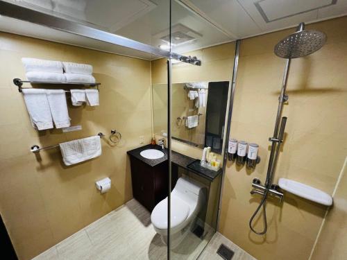 a bathroom with a shower and a toilet and a sink at Serenti Hotel Saipan in Garapan