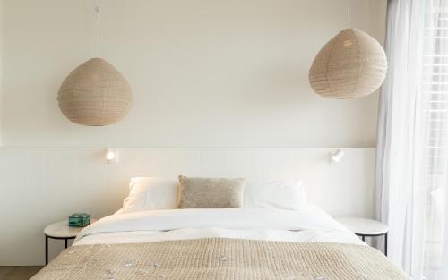 a bedroom with white walls and a bed with two tables at Aquabelle Apartments in Rye