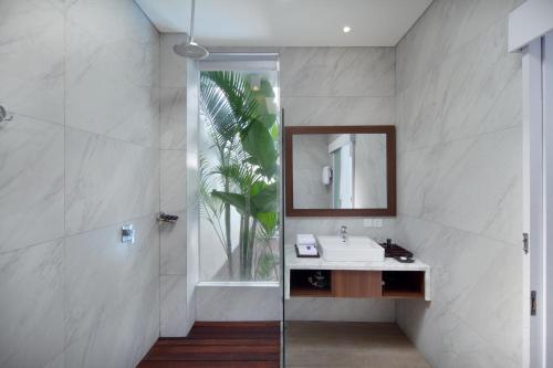 a bathroom with a sink and a mirror and a shower at The Grand Daha Luxury Villas in Seminyak