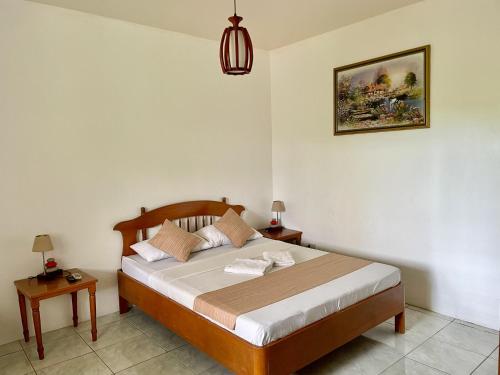 um quarto com uma cama e duas mesas e um candeeiro em Lapu-Lapu Cottages & Restaurant em Mactan