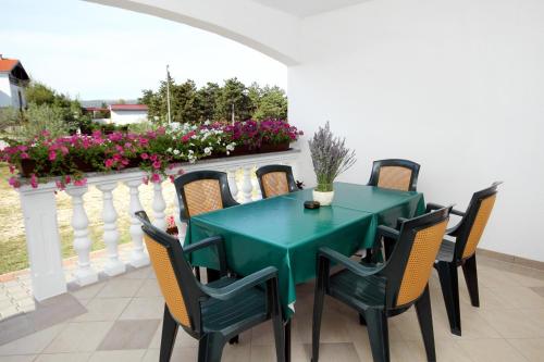 a green table and chairs on a balcony with flowers at Apartments with a parking space Seline, Paklenica - 6603 in Starigrad