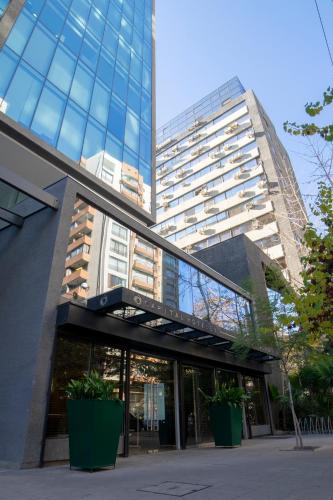 a tall building with glass windows in a city at Hotel Capital Bellet in Santiago