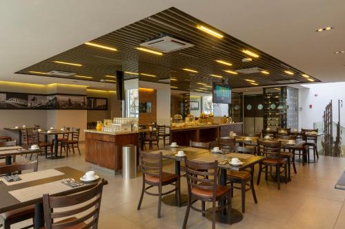 a restaurant with tables and chairs and a bar at Hotel Capital Bellet in Santiago