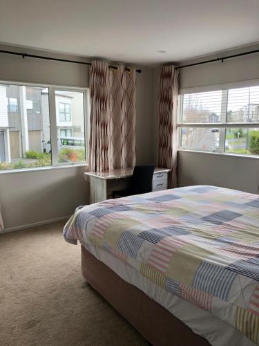 a bedroom with a bed and two windows at Brand new bedroom in Karaka (Auckland) in Auckland