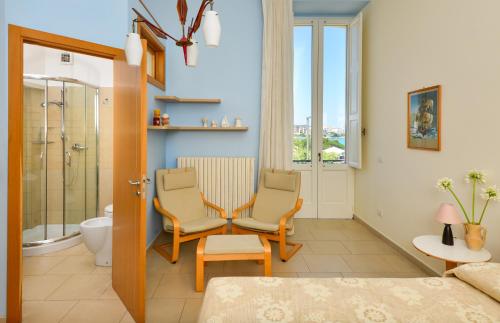 een slaapkamer met 2 stoelen en een badkamer met een douche bij Balcone su Otranto in Otranto