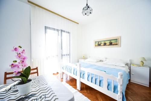 a white bedroom with a bed and a table at Apartments with parking space Zadar - Diklo, Zadar - 6453 in Diklo