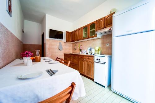 a kitchen with a white table and a refrigerator at Apartments with parking space Zadar - Diklo, Zadar - 6453 in Diklo