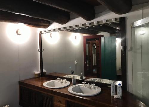 La salle de bains est pourvue de 2 lavabos et d'un grand miroir. dans l'établissement Pousada Travessia - Minas Gerais, à Três Pontas