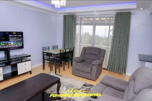 a living room with a tv and chairs and a table at Luxe Furnished Apartments in Meru