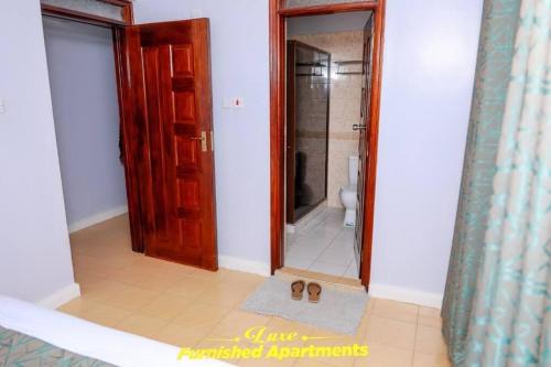 a bathroom with a toilet and a doorway with a mirror at Luxe Furnished Apartments in Meru