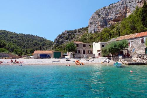 a group of people laying in the water on a beach at Apartments by the sea Cove Zarace - Gdinj, Hvar - 8712 in Gdinj