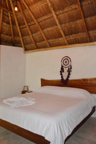 a bedroom with a white bed with a wooden headboard at Aldea Che-Eek , con acceso a un club de playa privado in Bacalar