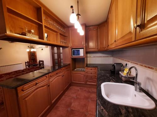 una cocina con armarios de madera y fregadero en ESPECTACULAR CASA RURAL CA L'ESQUERRÉ, en Cerviá