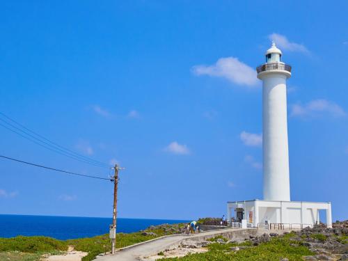 a lighthouse on top of a hill next to the ocean at ミチ旅ホテル 読谷 in Yomitan