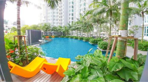 - une piscine dans un bâtiment avec des chaises jaunes et des palmiers dans l'établissement Holi 1Medini Themed Suites, à Nusajaya