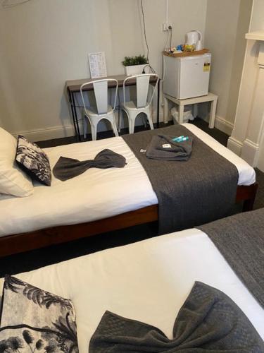 two beds in a room with chairs and a table at Cornwall Hotel in Moonta