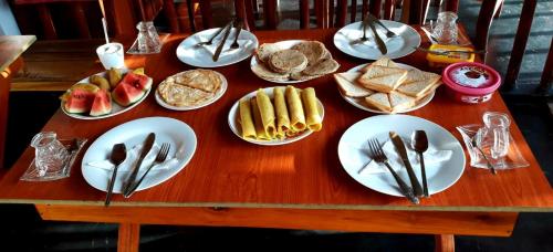 a wooden table with plates of food and utensils at Rainbow Sky Cottage in Ella