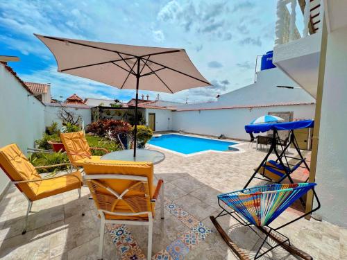 een patio met stoelen, een parasol en een zwembad bij Anapoima -Liberia in Anapoima