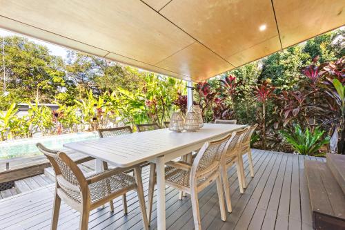 Una mesa blanca y sillas en una terraza de madera. en Styled 3 BR Tropical Family Home w Pool at Coolum, en Coolum Beach