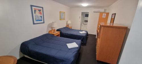 a hotel room with two beds and a cabinet at Queensport Tavern And Motel in Brisbane
