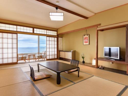 een woonkamer met een tafel en een televisie bij Hotel Sanrakuso in Shirahama