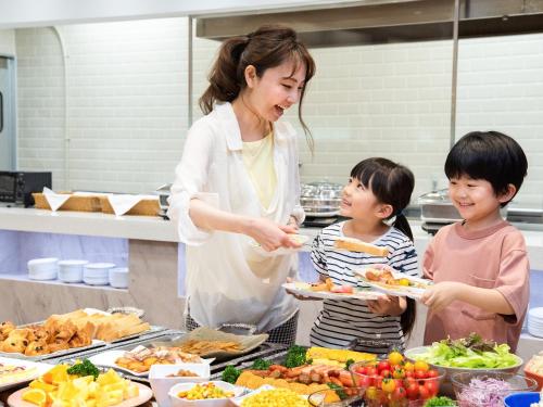 a woman and two children in a kitchen preparing food at Hotel Sanrakuso in Shirahama