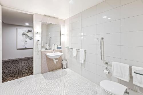 a white bathroom with a sink and a toilet at The Colmslie Hotel in Brisbane