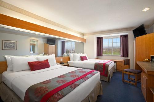 a hotel room with two beds and a desk at Ramada by Wyndham Bloomington I-55 and I-74 IL in Bloomington