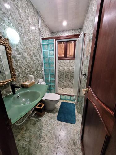 La salle de bains est pourvue d'un lavabo vert et de toilettes. dans l'établissement Tokoau Uta, à Moorea
