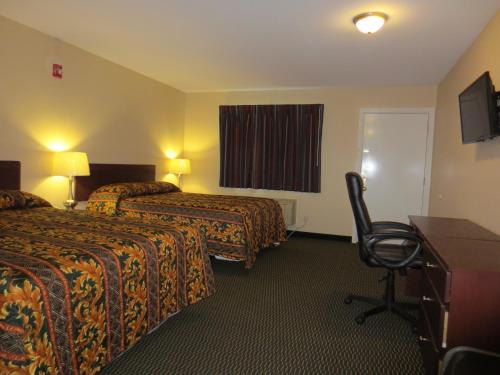 a hotel room with two beds and a desk and a chair at Wayne Motel in Fort Wayne
