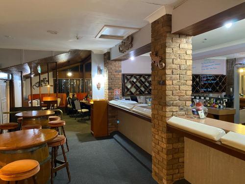 a restaurant with a bar and some tables and chairs at Gateway Motor Inn in Narrandera