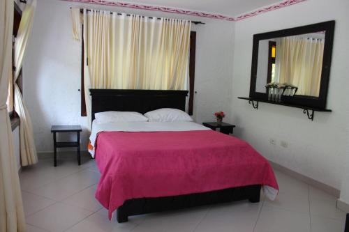 een slaapkamer met een groot bed en een roze deken bij Centro Vacacional Paraiso Termal in Tibirita