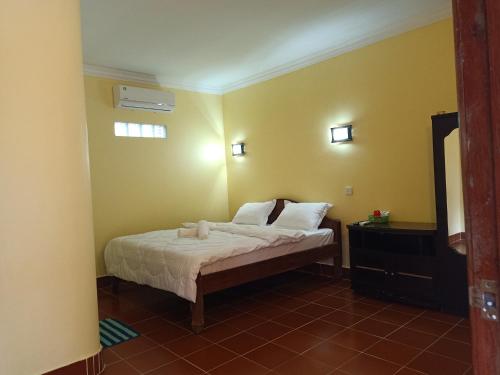 a bedroom with a bed in a room with yellow walls at Pina House in Kep