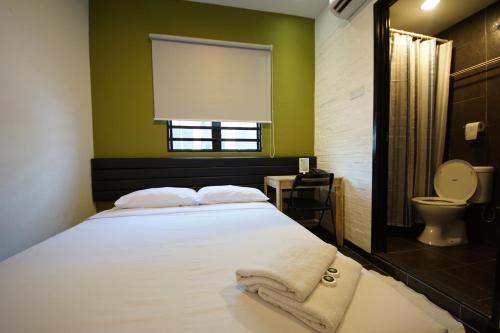 a bedroom with a bed and a toilet and a window at Tulip Hotel in Ipoh