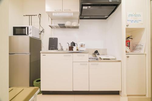 a kitchen with white cabinets and a refrigerator at La Lumiere Oroku in Akamine