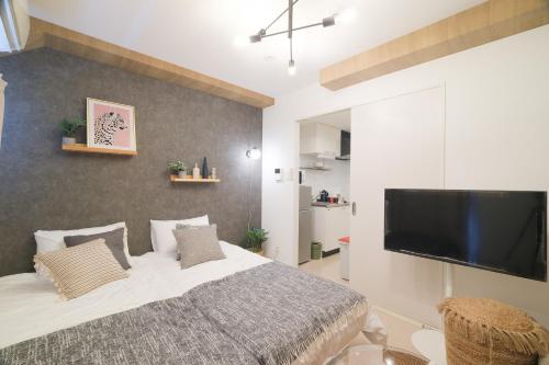 a bedroom with a large bed and a flat screen tv at La Lumiere Oroku in Akamine