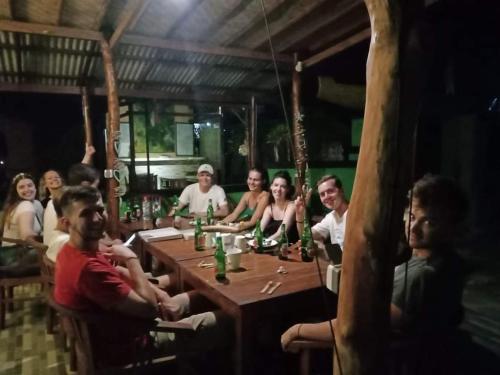a group of people sitting around a wooden table at Devadav Hostel (Bunk Bed) Nusa Lembongan in Nusa Lembongan