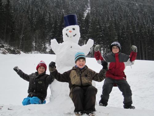 three people posing in front of a snowman at Alpenapart Walch in Jerzens