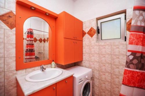 une salle de bains orange avec un lave-linge et un lavabo. dans l'établissement House just on the beach -included 2 canoe, 2 bicycles, à Ravdhoúkha
