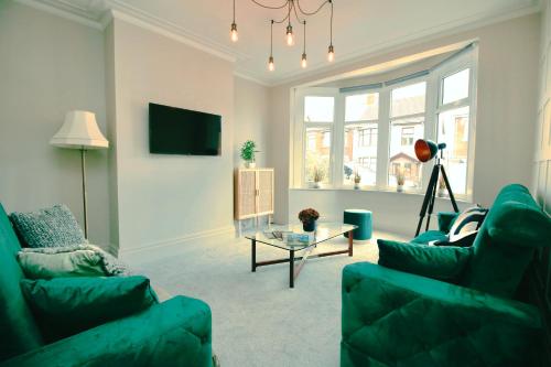 a living room with two green couches and a table at XxHot TubxX 4Bed semi, sleeps 8, 2 bathrooms in Blackpool