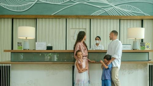 a family standing in front of a counter in a hospital at Holiday Inn Bali Sanur by IHG in Sanur