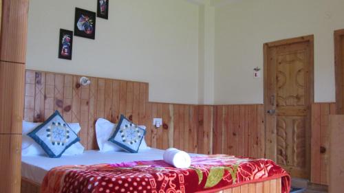 a bedroom with a bed with a red and white blanket at MOZO Inn&Cafe Jibhi in Banjār