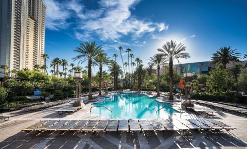 a pool at a resort with chaise lounge chairs and palm trees at SKYLOFTS at MGM Grand in Las Vegas
