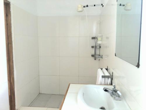 La salle de bains blanche est pourvue d'un lavabo et d'un miroir. dans l'établissement Bay View Apartment 4 - Canouan Island, à Canouan