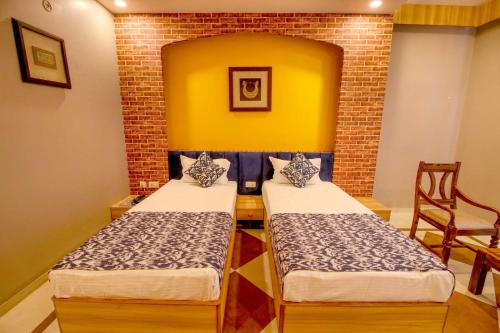 two beds in a room with a brick wall at Gems Suites-A Boutique Stay in Jaipur
