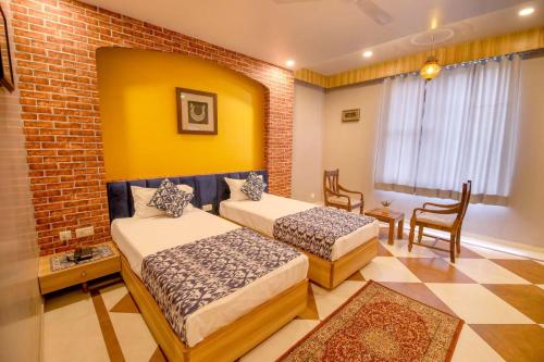 a bedroom with two beds and a brick wall at Gems Suites-A Boutique Stay in Jaipur