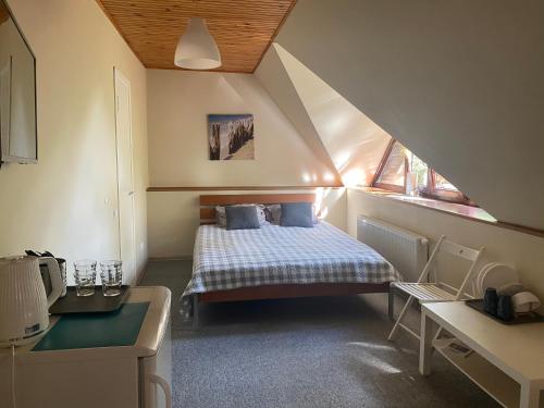 um pequeno quarto com uma cama no sótão em Pušų kiemas em Palanga